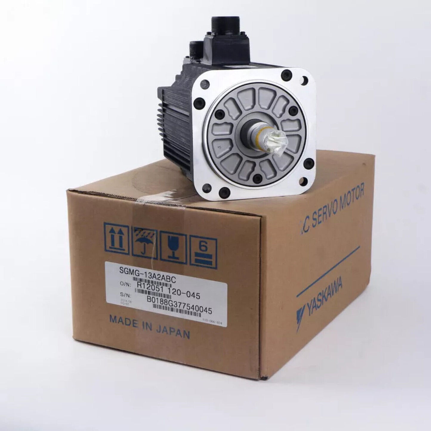 YASKAWA SGMG-13A2ABC AC servo motor on box. Made in Japan. Industrial automation part, black and silver.