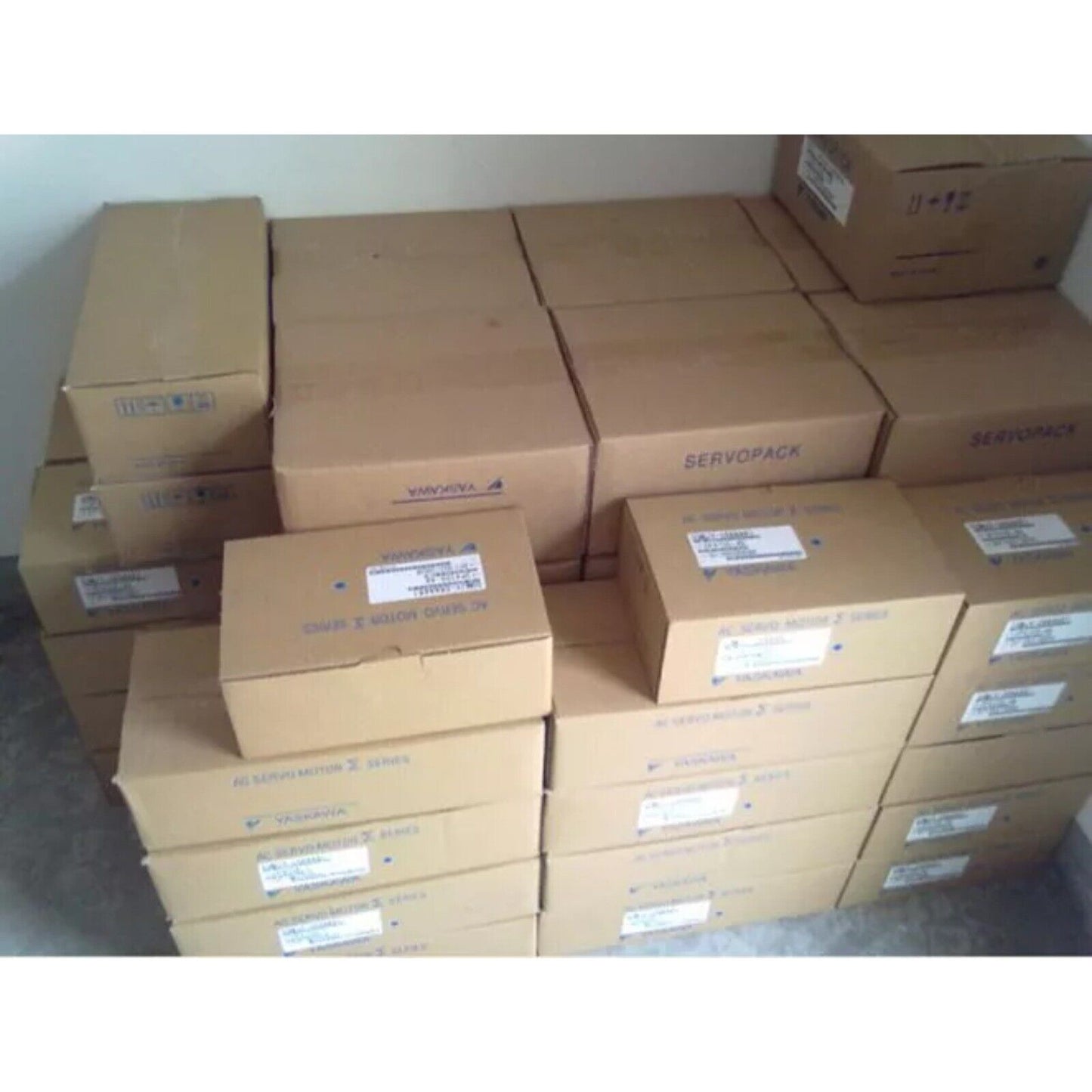Yaskawa ServoPack boxes stacked, industrial automation equipment, new SGD7S-5R5A00A002 servo drives ready for shipment.