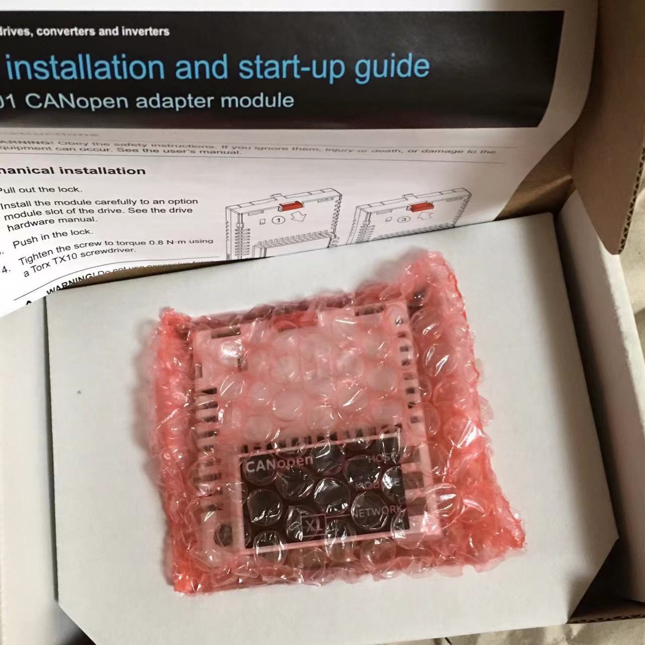 ABB FCAN-01 CANopen adapter module, packaged in bubble wrap, installation guide visible, PLC component.