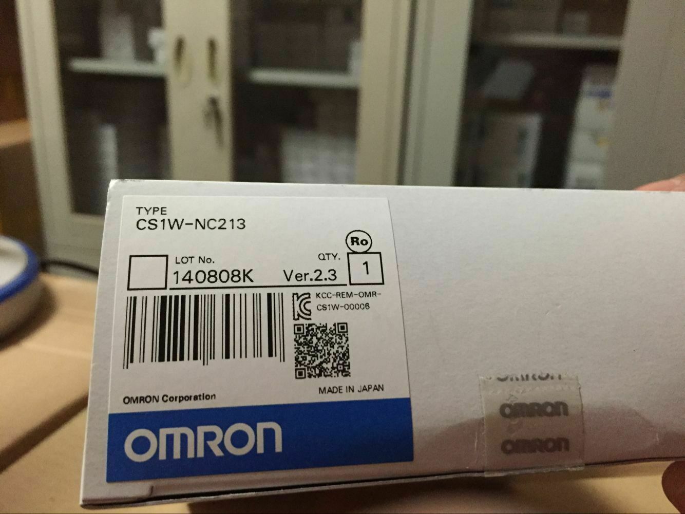 Omron CS1W-NC213 controller packaging showing product details, including lot number, version, and Made in Japan.