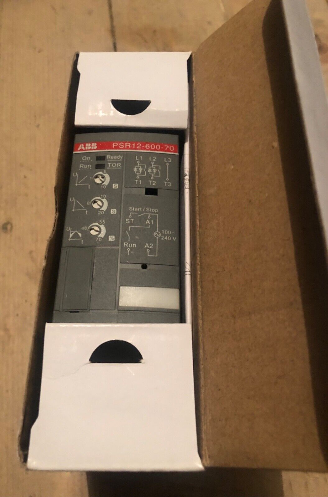ABB PSR12-600-70 soft starter inside box. Gray industrial automation component with labels for terminals and control.