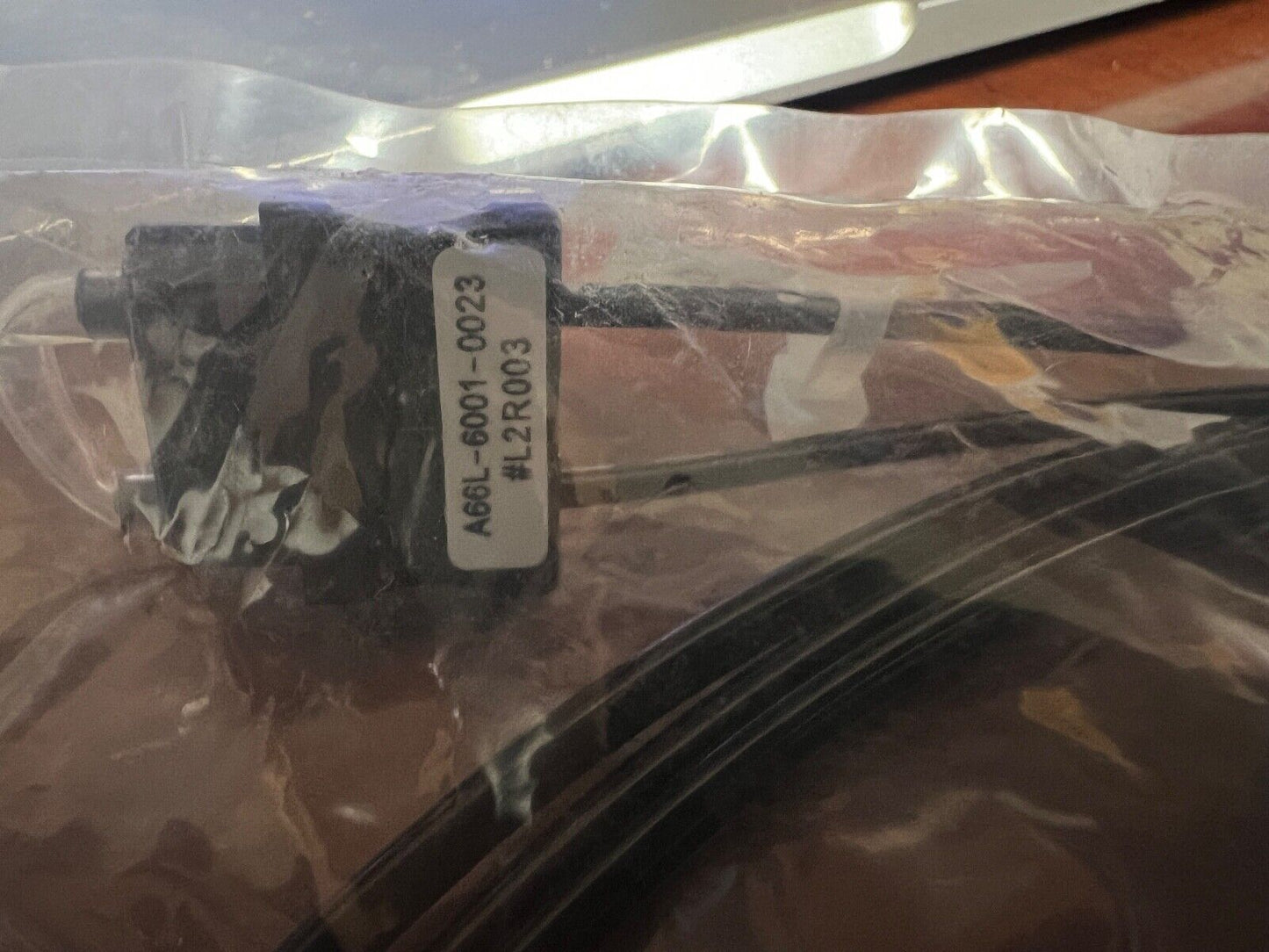 FANUC A66L-6001-0023 SERVO OPTICAL FIBER cable inside a clear bag, industrial automation PLC component.