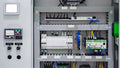 An electrical control panel with a PLC, HMI screen, and organized wiring.