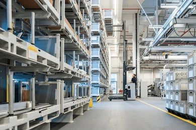 A forklift operates in a large, well-lit warehouse with high shelving units.