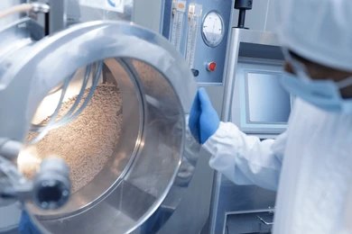 Scientist inspecting pharmaceutical products inside a large industrial drum.