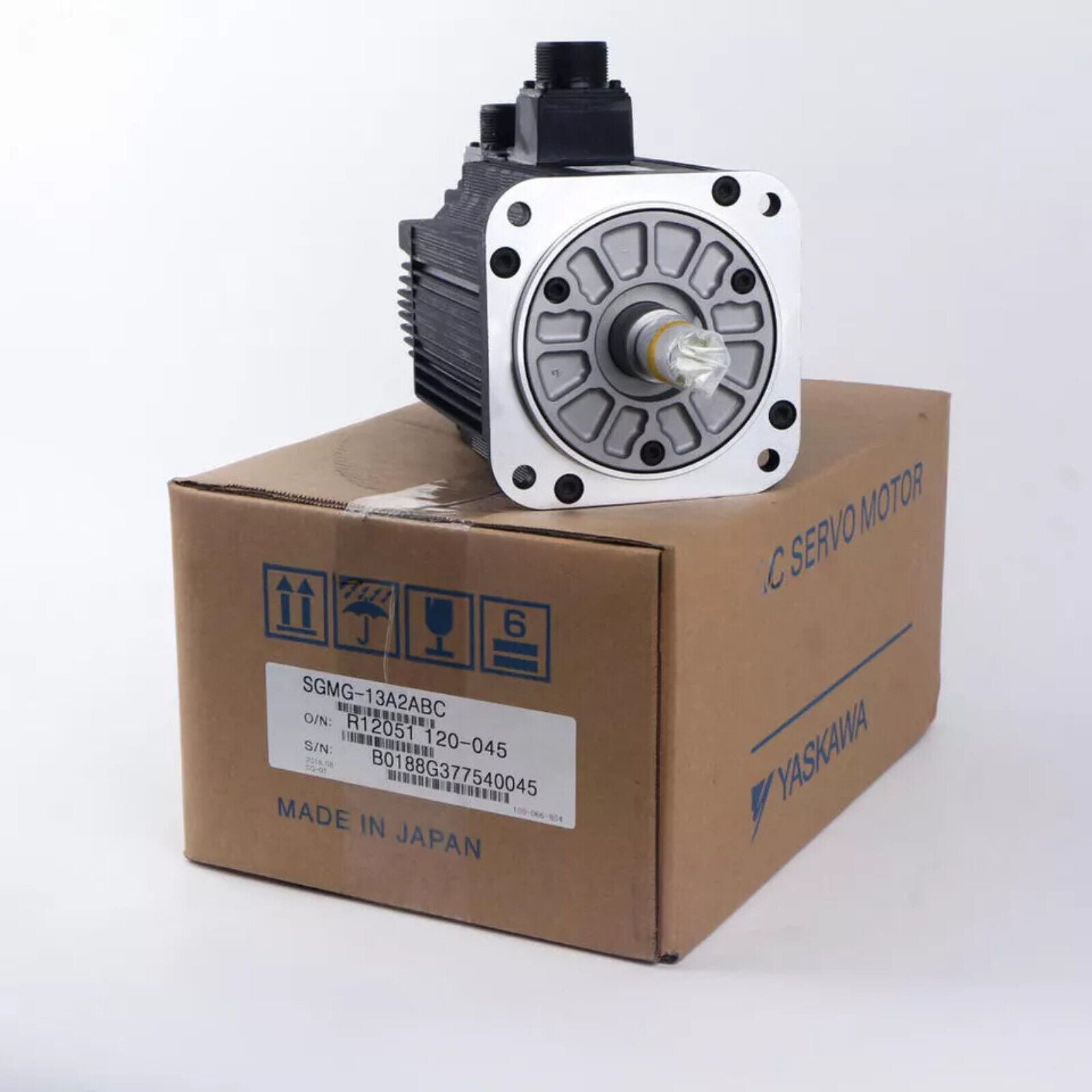 YASKAWA SGMG-13A2ABC AC servo motor on box. Made in Japan. Industrial automation part, black and silver.