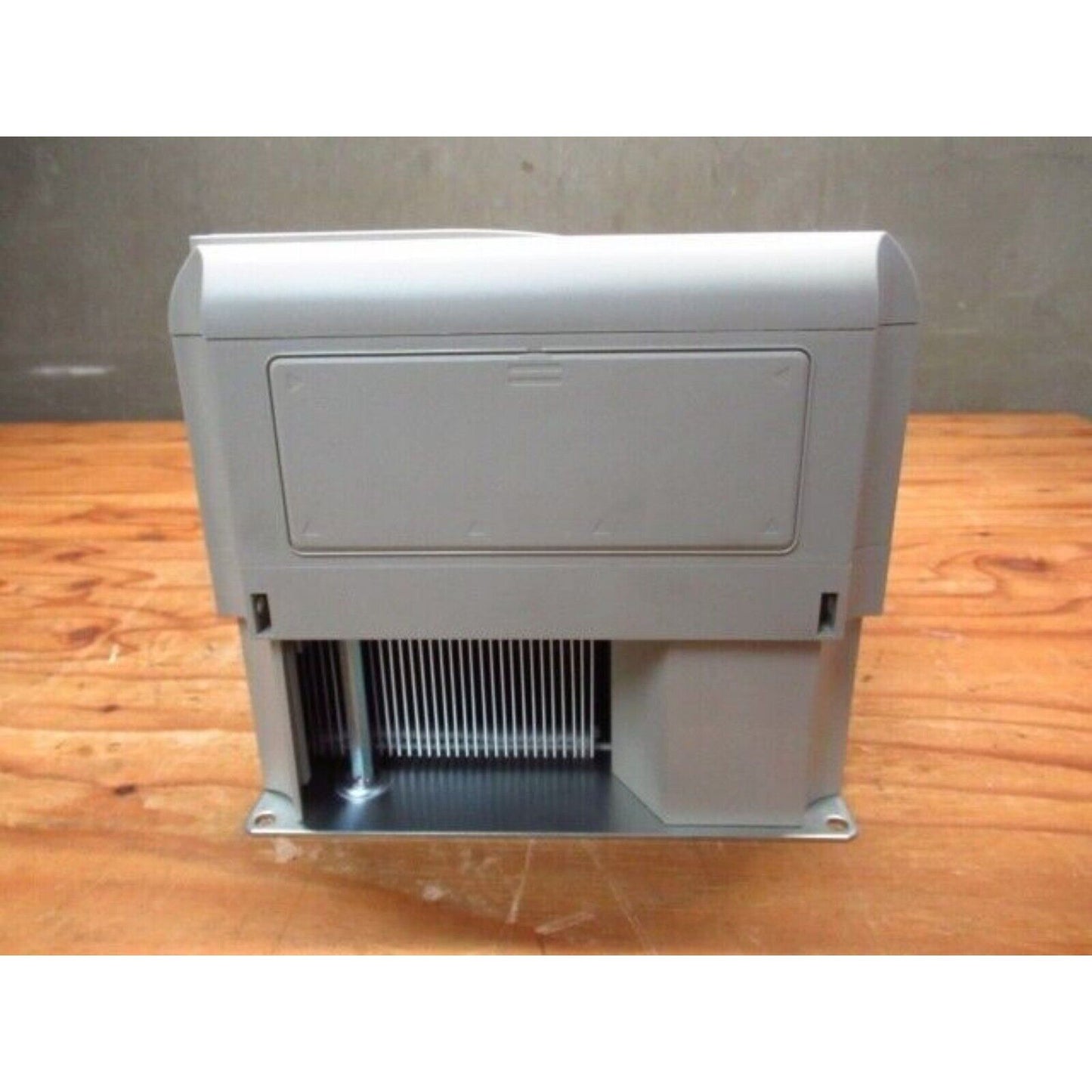 YASKAWA G7 Inverter, front view, gray industrial automation part on wood. Featuring cooling fins.