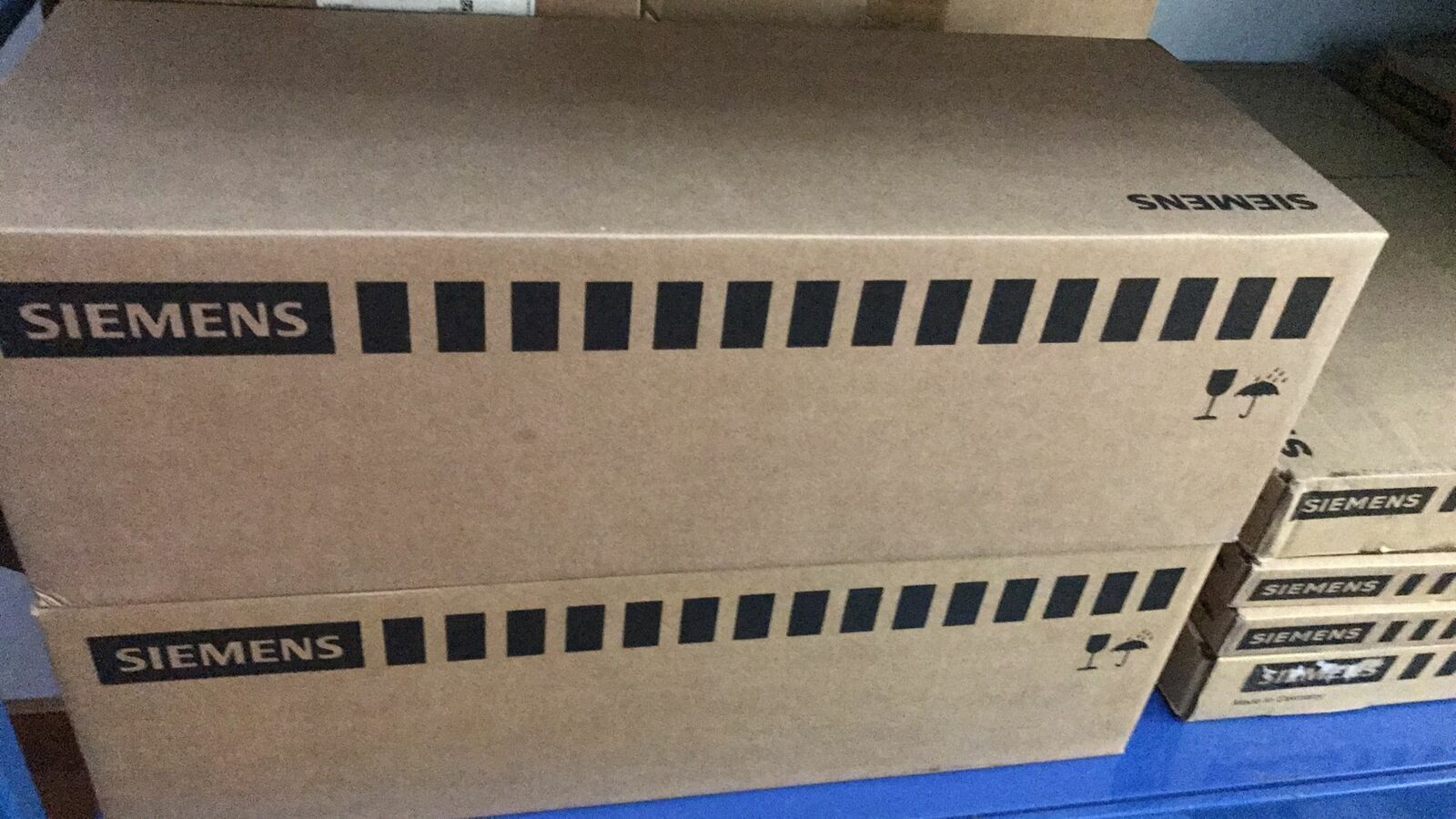 Siemens industrial automation product boxes stacked in a warehouse, with fragile handling symbols.