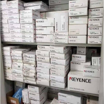 KEYENCE industrial automation parts stock, various safety door sensors and components in boxes on shelves.