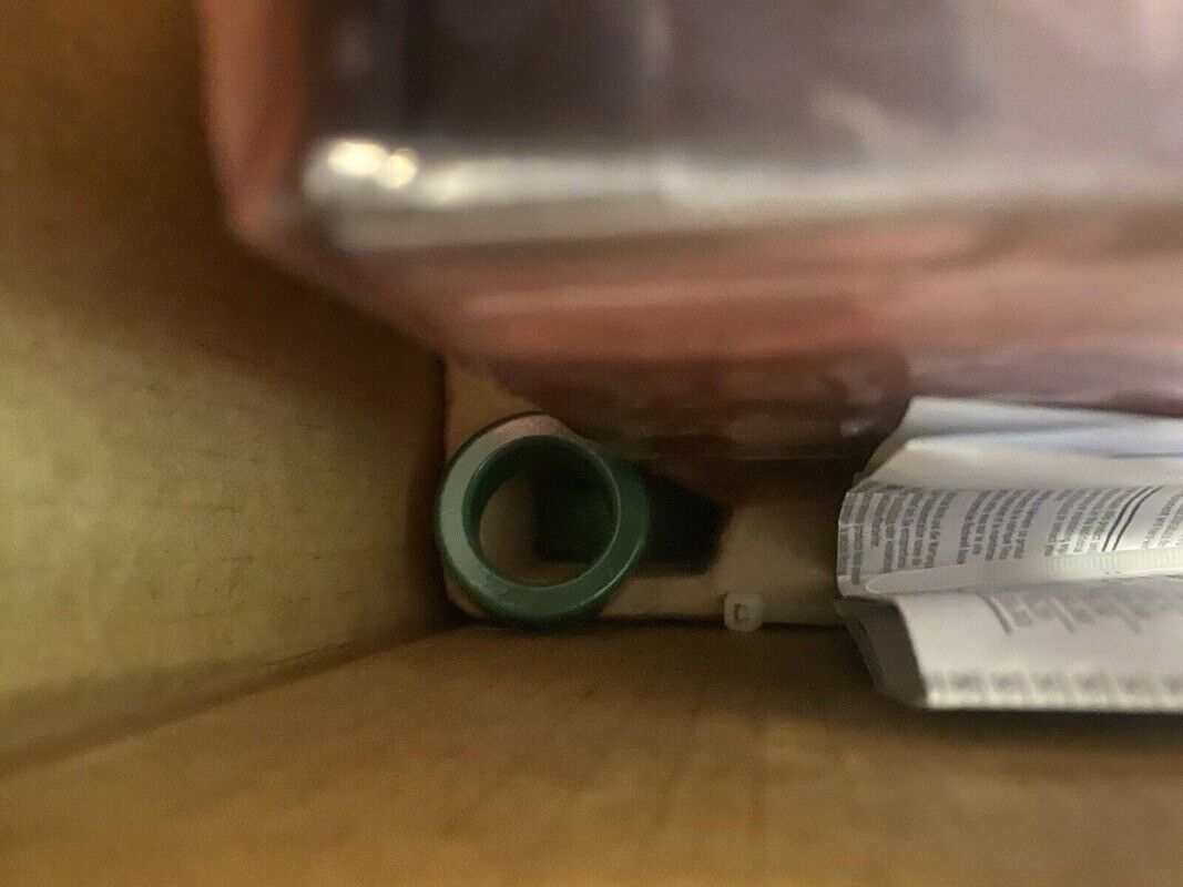 Allen-Bradley PLC component, green circular part and paperwork inside box, PLC automation equipment.