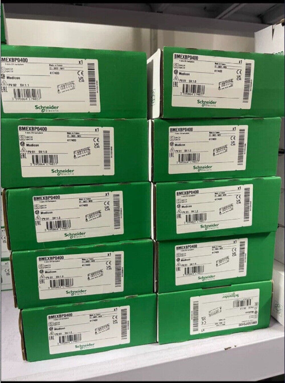 Schneider Electric BMEXBP0400 I/O modules in green boxes, industrial automation parts.