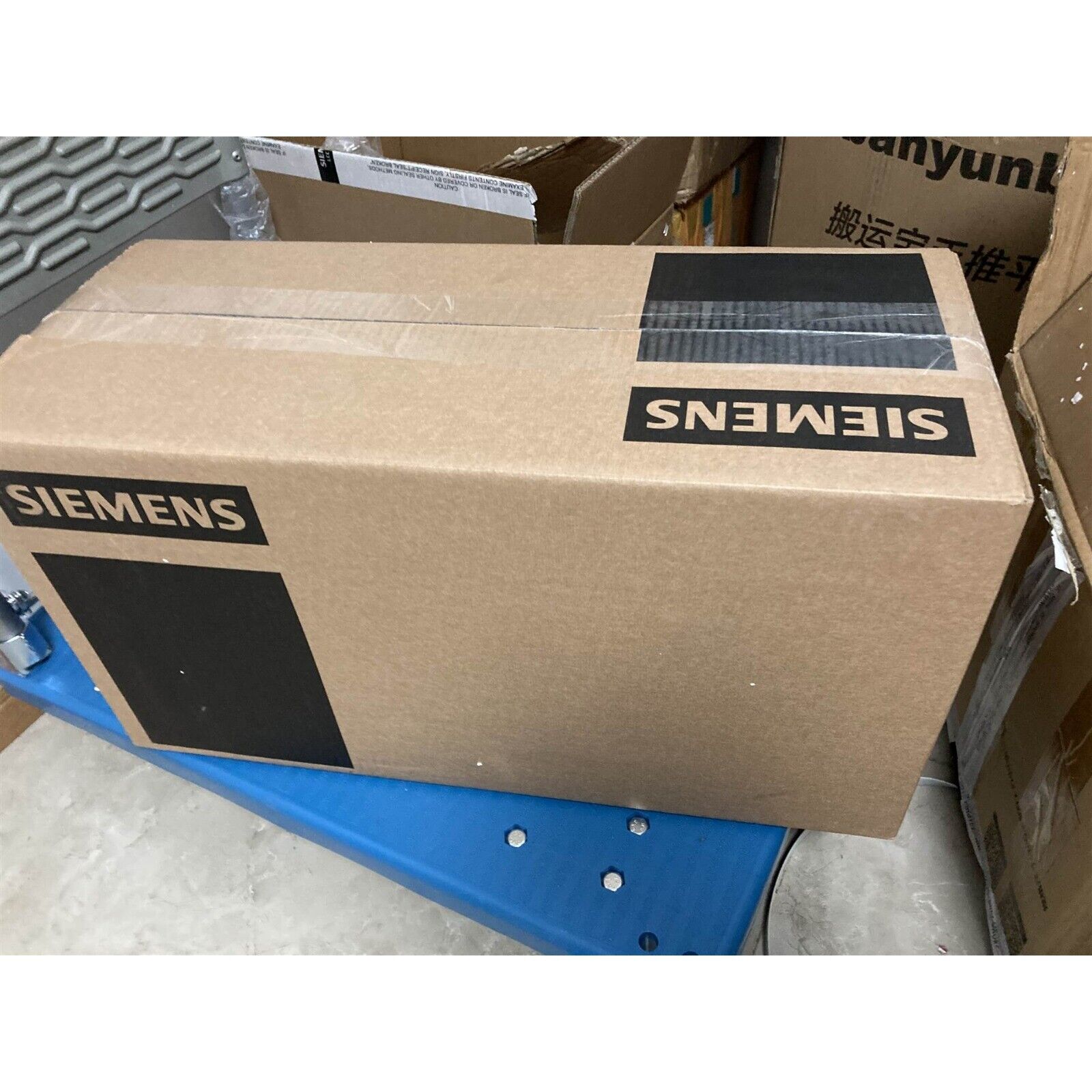 Siemens industrial automation product packaging box, cardboard with Siemens logo, ready for shipping.