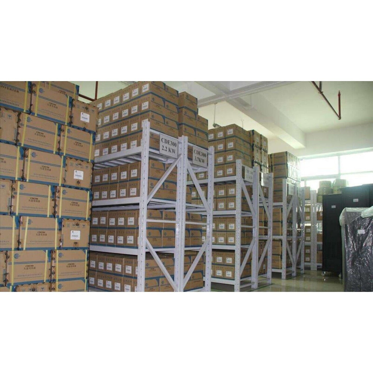 Industrial automation parts warehouse, boxes of CDE300 2.2KW and 3.7KW products stored on metal shelving.