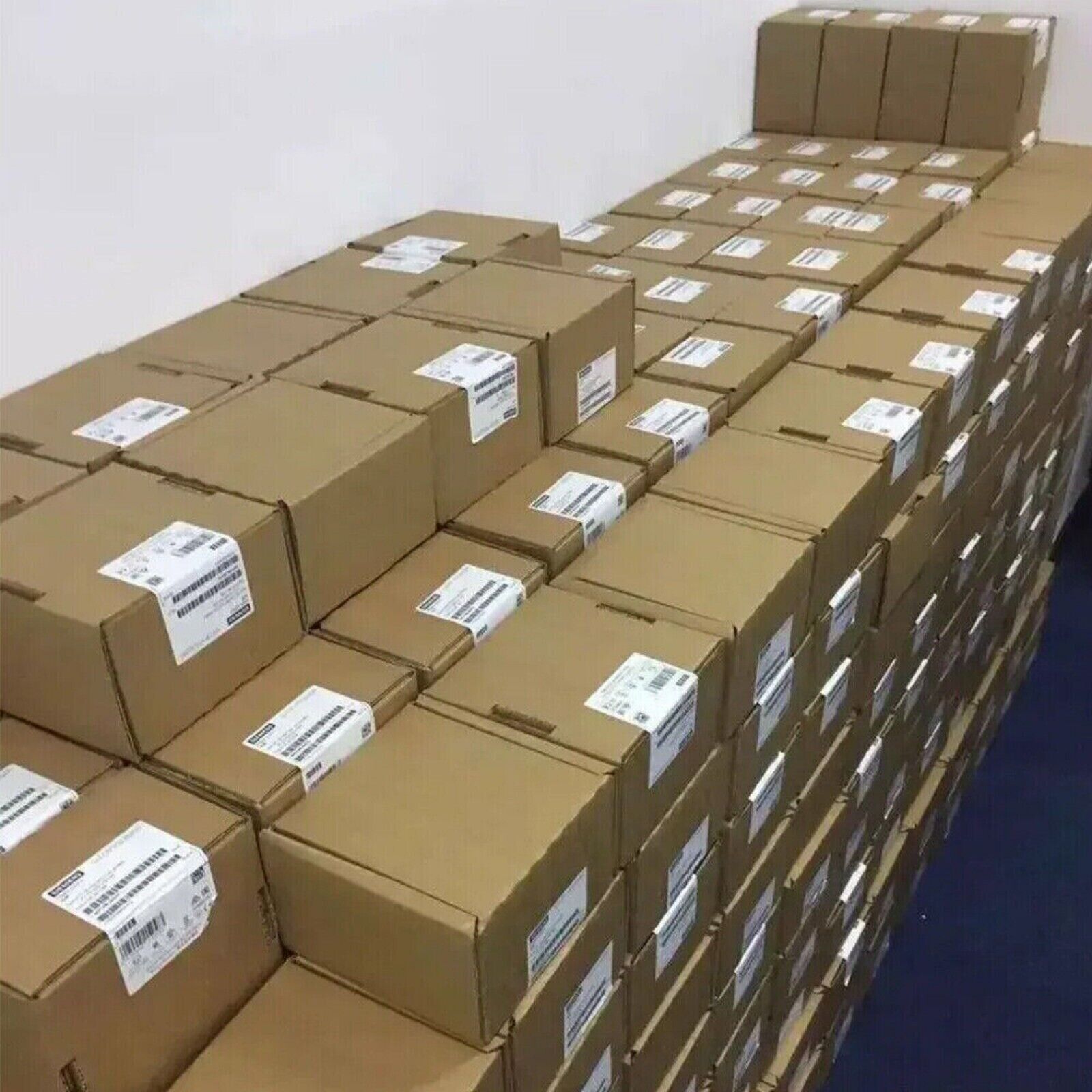 Stack of Siemens PLC module boxes ready for shipment. Industrial automation parts in a warehouse setting.