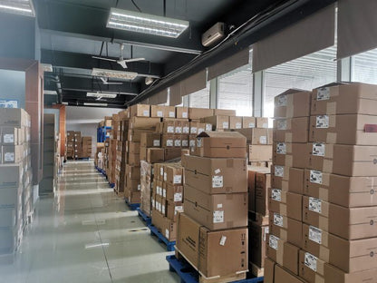 Industrial automation parts warehouse with stacked boxes on pallets, featuring Allen-Bradley and other brand components.