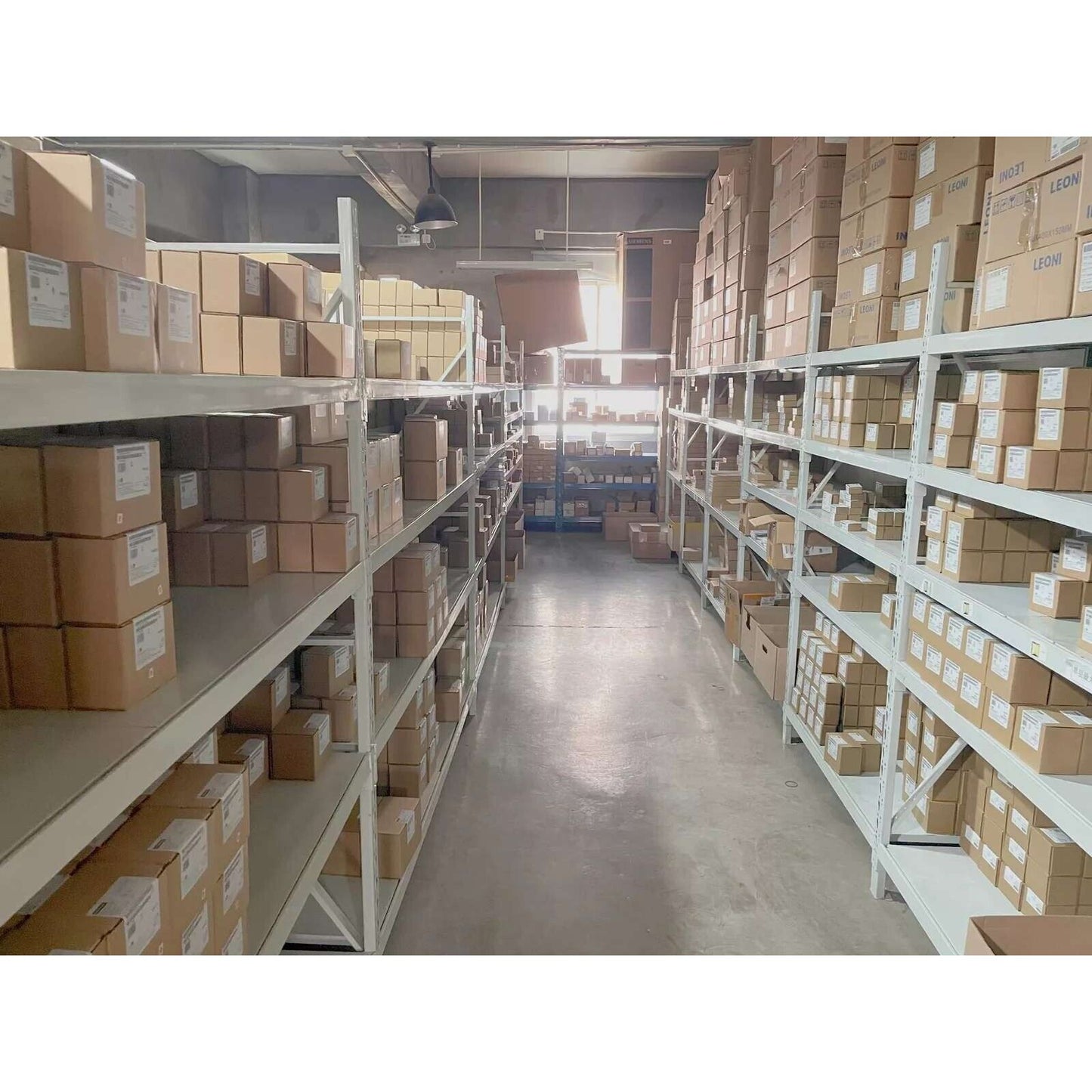 Warehouse shelves stocked with industrial automation parts, including Siemens VFDs and components.