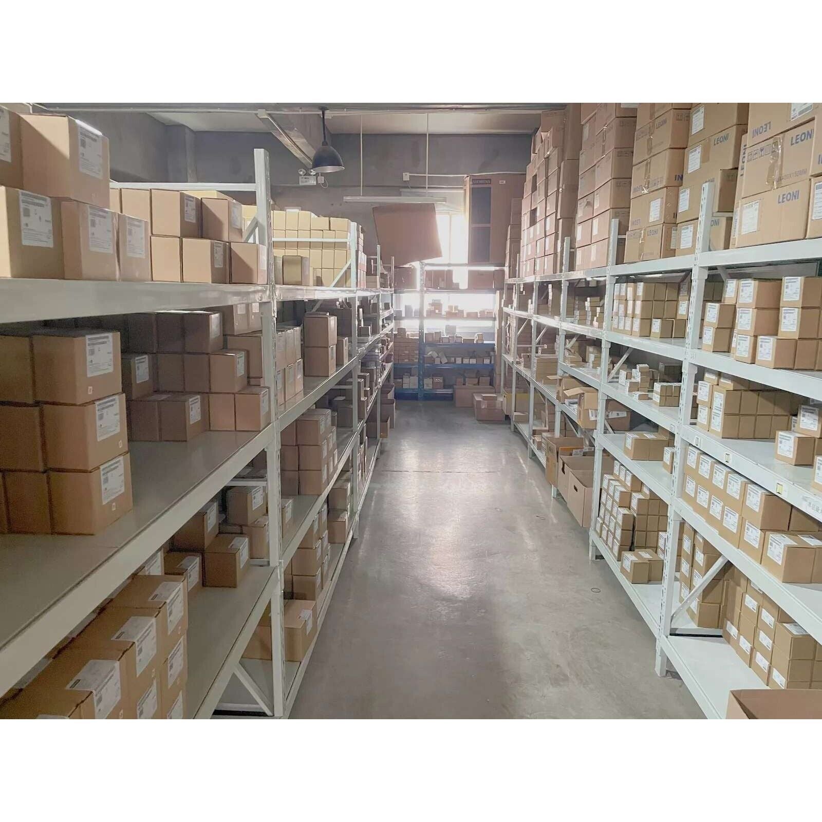 Warehouse shelves stocked with industrial automation parts, including Siemens VFDs and components.
