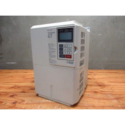 Yaskawa G7 VFD. Industrial automation equipment with LCD display and control panel. Beige unit on wood.