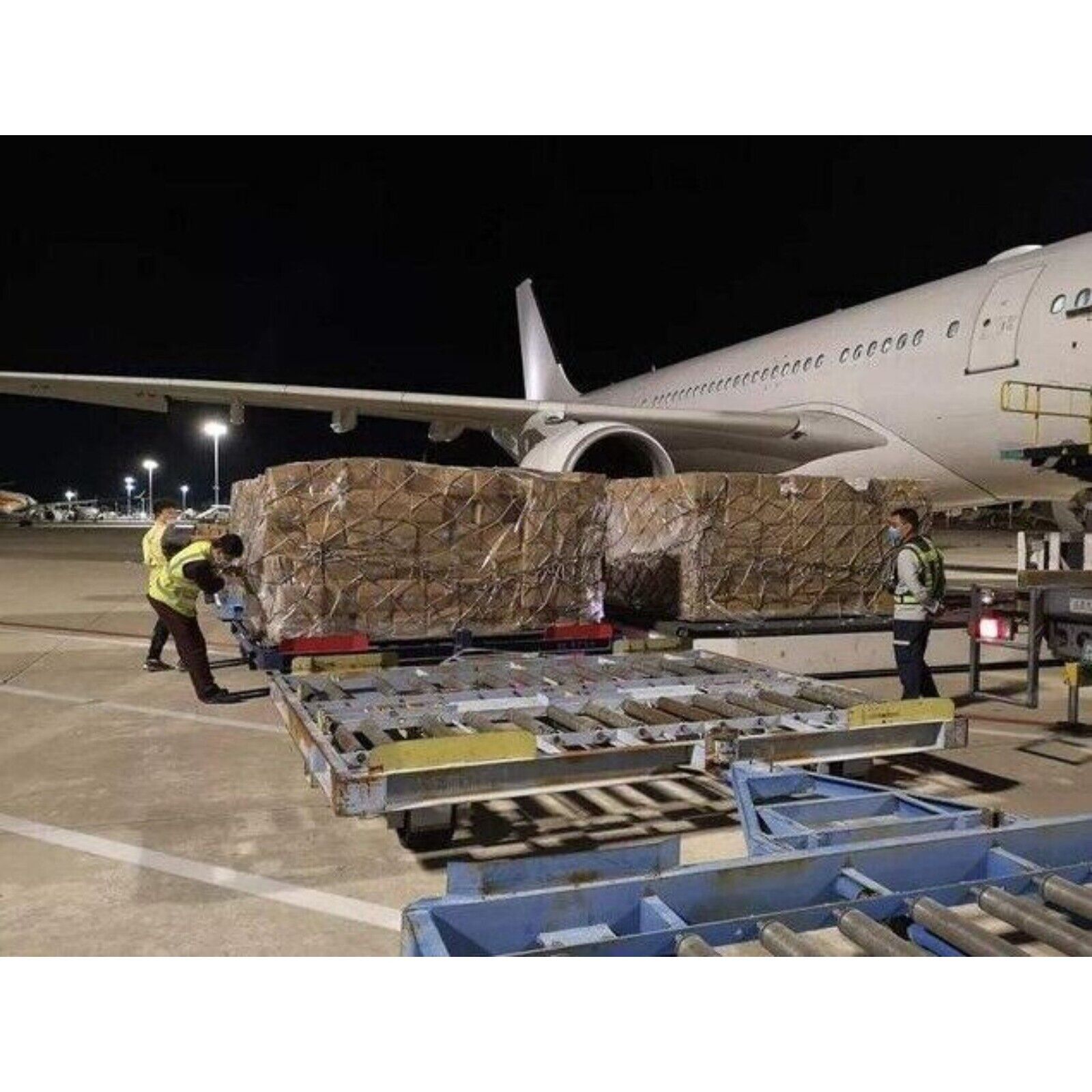 Air cargo loading: Industrial automation parts being loaded onto a cargo plane at night.