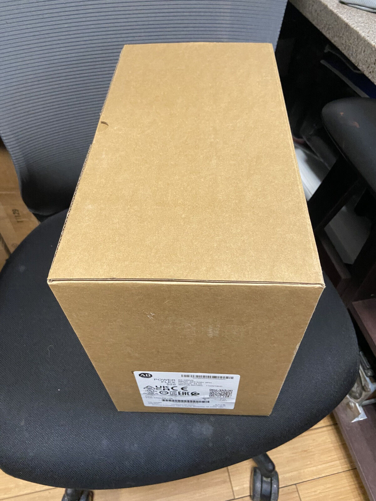 Allen-Bradley PowerFlex 525 AC Drive box, product packaging on chair