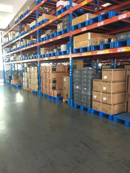 Warehouse storage of Mitsubishi FR-E740 inverters on metal racks and pallets, industrial setting