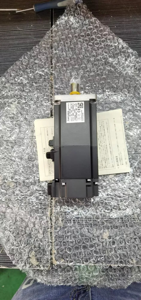 Mitsubishi HF-MP43B AC Servo Motor, industrial automation part, black metal body and labels, bubble wrap protection.