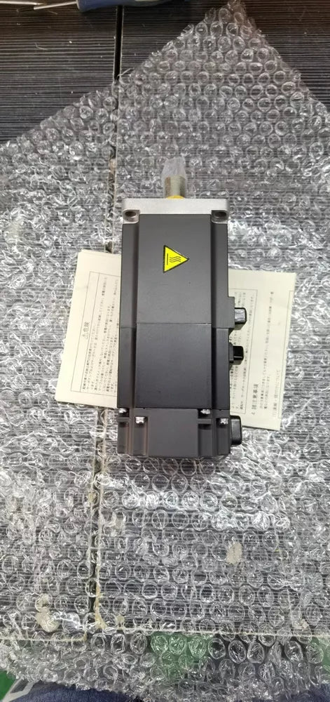 Mitsubishi HF-MP43B servo motor, industrial automation part, black metal body, in bubble wrap, with labels.