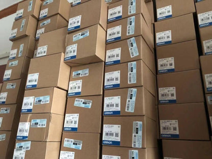 Stack of new Omron CJ1W-CLK23 Controller Module boxes ready for shipping, new PLC units for industrial automation.