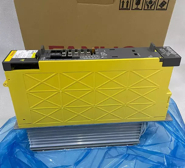 FANUC A06B-6132-H003 Servo Drive in yellow. Front view of the product on a blue surface with packaging in the background.
