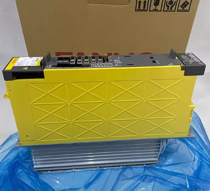 FANUC A06B-6132-H003 Servo Drive in yellow. Front view of the product on a blue surface with packaging in the background.
