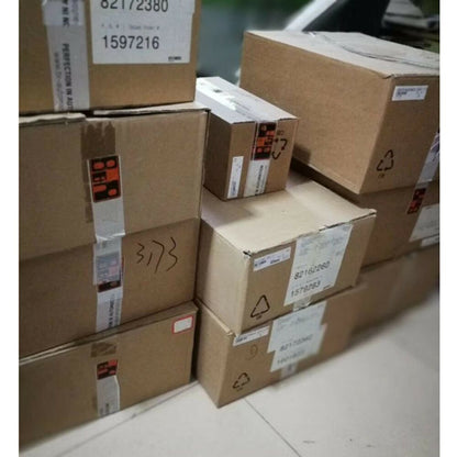 Cardboard boxes stacked for industrial automation parts, with labels showing part numbers and shipping information.