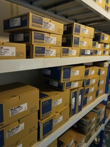 Mitsubishi MR-J2S-40B-EE085 Servo Drive units in boxes on shelves, industrial automation parts.