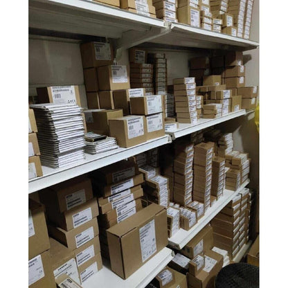 Warehouse stock of industrial automation parts, including Siemens boxes and other components on shelves.