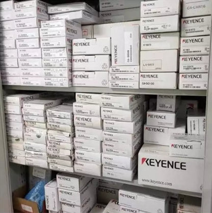 KEYENCE industrial automation parts in storage, various models and packaging displayed.