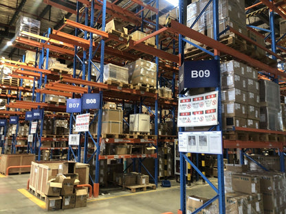 Warehouse storage of Mitsubishi FR-E740-2.2K-CHT inverters and industrial automation parts, safety signage visible.